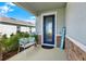 Welcoming front porch featuring a blue front door, bench with pillows, stone accents and lush greenery at 10432 High Noon Trl, Parrish, FL 34219