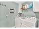 Functional laundry room equipped with washer, dryer, overhead storage, and decor at 10432 High Noon Trl, Parrish, FL 34219