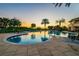 A serene swimming pool at sunset, surrounded by palm trees and lush landscaping at 1504 Valley Forge Blvd, Sun City Center, FL 33573