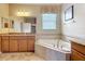 Bright bathroom featuring double sinks, cabinets, a tub, and a window at 19724 Fort King Run, Brooksville, FL 34601