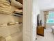 Open linen closet with white shelves, revealing a bedroom beyond at 19724 Fort King Run, Brooksville, FL 34601