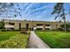 Walkway leading to a multi-Gathering residential building with manicured landscaping and mature trees at 36750 Us Highway 19 N # 6-214, Palm Harbor, FL 34684