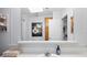 Bathroom features wood vanity, tub/shower reflected in large mirror with vanity lighting and skylight at 36838 Tara Ave, Zephyrhills, FL 33542