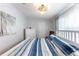 Bedroom features bright light fixture, view of door and artwork, and comfortable striped bed at 36838 Tara Ave, Zephyrhills, FL 33542