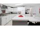 Kitchen boasts white cabinets, stainless appliances, a center island with seating, and open shelving for décor at 36838 Tara Ave, Zephyrhills, FL 33542
