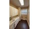 A well-lit laundry room features a white sink and cabinets, window with blinds, and dark wood-look floors at 4425 Merrick Run Ln, Valrico, FL 33596