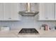 Close-up of a modern gas stovetop set within a white quartz countertop and stylish white backsplash at 5318 Wishing Arch Dr, Apollo Beach, FL 33572