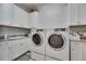 Well-lit laundry room with white cabinetry, modern washer and dryer units, and ample counter space at 5318 Wishing Arch Dr, Apollo Beach, FL 33572