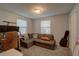 A cozy bedroom showcasing a sofa, natural light from two windows and a guitar case beside the closet door at 5704 Half Moon Lake Rd, Tampa, FL 33625