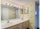 Bathroom featuring a dual sink vanity, bright lighting, and unique wallpaper at 6323 Newtown Cir # 23A1, Tampa, FL 33615