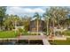 Stunning view of the home from the water, featuring a screen enclosed porch, wooden dock, and lush greenery at 680 George S St, Tarpon Springs, FL 34688