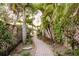 Picturesque backyard with a brick pathway winding through tropical foliage towards a waterfront view at 680 George S St, Tarpon Springs, FL 34688