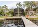 Expansive backyard with a screened-in pool, lush landscaping, and a waterfront view at 680 George S St, Tarpon Springs, FL 34688