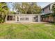 Spacious backyard with lush green grass, patio and a view of a gray home with large windows at 680 George S St, Tarpon Springs, FL 34688