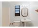 Bathroom featuring a pedestal sink, three-light vanity, and a window at 680 George S St, Tarpon Springs, FL 34688
