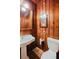 Cozy bathroom featuring wood paneling, a pedestal sink, and a toilet at 680 George S St, Tarpon Springs, FL 34688