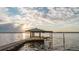 Picturesque dock with a covered seating area extends into the calm, sun-kissed water at sunset at 680 George S St, Tarpon Springs, FL 34688