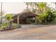 Stone façade garage featuring a stylish wooden carport with detailed landscaping at 680 George S St, Tarpon Springs, FL 34688