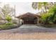 Stone façade garage featuring a stylish wooden carport with detailed landscaping at 680 George S St, Tarpon Springs, FL 34688