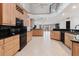 Bright kitchen with wooden cabinets, black countertops, and tile flooring overlooking the living area at 680 George S St, Tarpon Springs, FL 34688