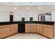 This kitchen features wood cabinets, a black countertop, and a black dishwasher at 680 George S St, Tarpon Springs, FL 34688