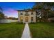 Charming two-story home with a manicured lawn and welcoming walkway leading to the front entrance under a twilight sky at 7125 6Th N Ave, St Petersburg, FL 33710