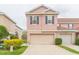 Two-story pink home with a two-car garage, black shutters, and well-maintained landscaping at 10011 Tranquility Way, Tampa, FL 33625