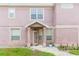 Front exterior view of a pink townhome with decorative door, manicured lawn, and neutral trim at 10011 Tranquility Way, Tampa, FL 33625