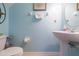 Cozy half-bathroom is painted with sky-blue, has a pedestal sink and elongated toilet at 10011 Tranquility Way, Tampa, FL 33625