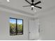 Bright bedroom with a modern ceiling fan, a large window overlooking lush greenery, and neutral decor at 14207 Fort Worth Cir, Port Charlotte, FL 33981