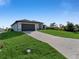 A modern one-story home with a two-car garage, set on a large lot with a paved driveway and green lawn at 14207 Fort Worth Cir, Port Charlotte, FL 33981