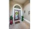 Charming front entrance with a decorative wreath, tiled entryway, seahorse decorations, and vibrant potted plants at 1727 Lakestone Dr, Trinity, FL 34655