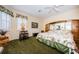 Spacious main bedroom with green carpet, a ceiling fan, and a large bed and closet with mirrors at 1727 Lakestone Dr, Trinity, FL 34655