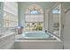 Bathroom featuring a large soaking tub under an arched window and separate glass-enclosed shower at 18521 Bittern Ave, Lutz, FL 33558