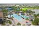 Aerial view of community resort-style pool, lounge chairs, palm trees and lush green spaces with neighborhood views at 19410 Indian Rock Pl, Lakewood Ranch, FL 34211