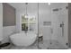 Bright main bathroom featuring a free standing tub, a large window, marble tile floors, and a glass shower at 2075 Warwick Dr, Oldsmar, FL 34677