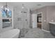 Bright bathroom featuring a free standing tub, a glass shower and marble tile floors at 2075 Warwick Dr, Oldsmar, FL 34677