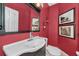 Stylish powder room featuring a red wall, vanity with a sink, and decorative wall art at 2075 Warwick Dr, Oldsmar, FL 34677
