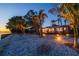 Stunning waterfront home exterior with illuminated outdoor space and lush tropical landscaping at twilight at 2158 Blossom S Way, St Petersburg, FL 33712