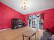 Living room with piano, chandelier, and red accent wall plus sliding doors to patio at 2300 S Shore Se Dr, St Petersburg, FL 33705