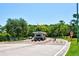 View of a gated community entrance with a guard house, lush landscaping, and an American flag waving at 2348 Rolling View Dr, Spring Hill, FL 34606