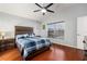 Inviting bedroom with wooden headboard, ceiling fan, and rich wood flooring at 25348 Flying Ebony Ln, Wesley Chapel, FL 33544