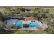 Aerial view of a community pool area with multiple pools, a playground, and ample seating at 25348 Flying Ebony Ln, Wesley Chapel, FL 33544