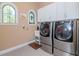 Bright laundry room with stainless steel washer and dryer, white cabinetry, utility sink, and arched windows at 4302 W San Pedro St, Tampa, FL 33629