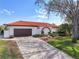 Charming single-story home with a red tile roof, manicured landscaping, arched entryway, and brick driveway at 4901 Lansing St Ne, St Petersburg, FL 33703
