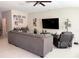 Spacious living room with a large sectional sofa, TV, ceiling fan, and neutral color palette at 4908 Wild Senna Blvd, Tampa, FL 33619