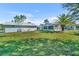 A backyard featuring a lawn, tropical trees and shrubbery, and a white picket fence at 541 Ridgecrest Dr, Punta Gorda, FL 33982