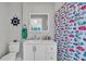 Stylish bathroom with colorful shower curtain, white vanity, and nautical decor at 541 Ridgecrest Dr, Punta Gorda, FL 33982