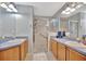 Dual sink bathroom with a glass-enclosed shower and spacious countertops with natural wood cabinets at 6809 Exeter Park Pl, Apollo Beach, FL 33572