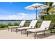 View of three lounge chairs on a patio with a beautiful lawn and waterfront in the distance at 72 Adalia Ave, Tampa, FL 33606